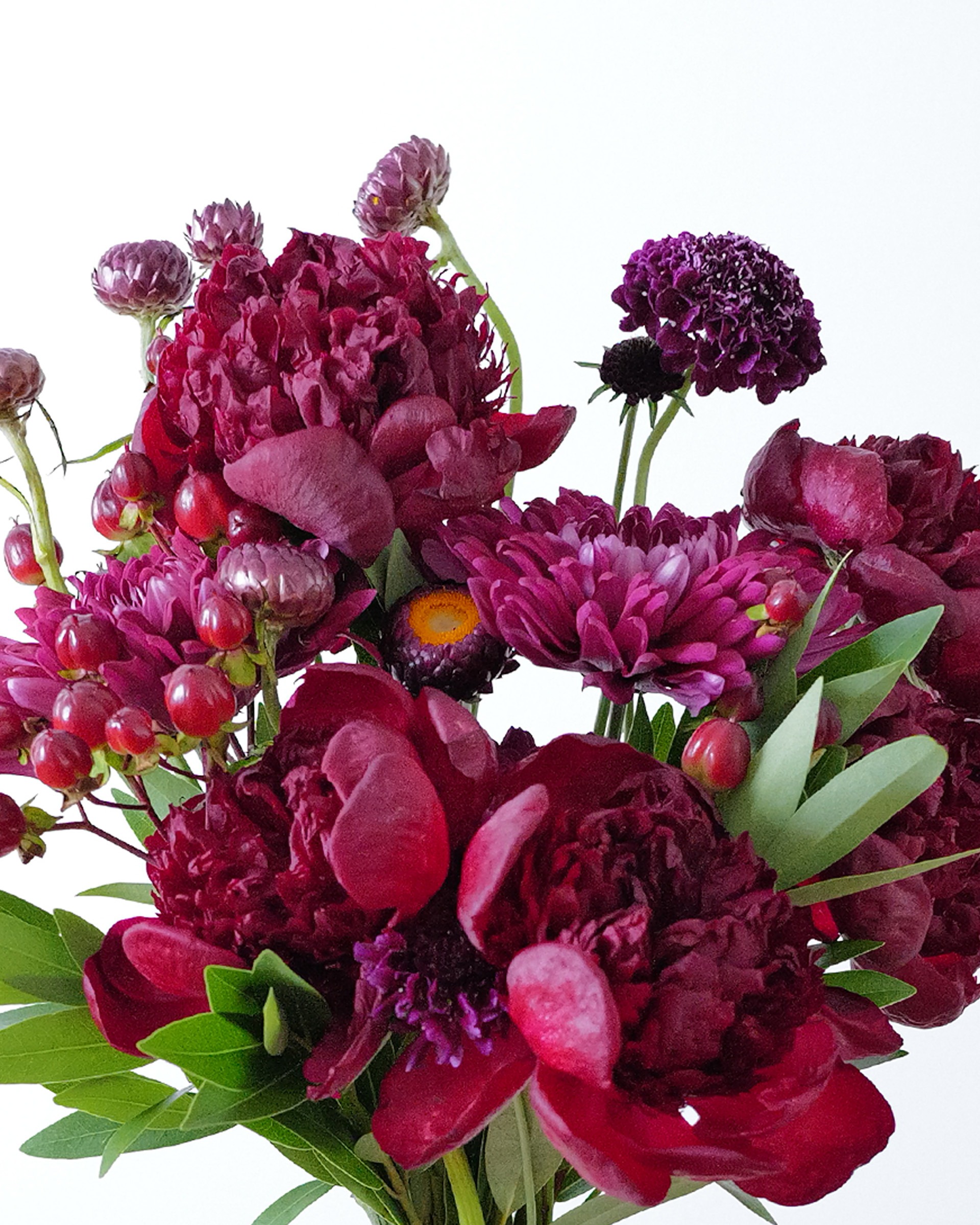 Close view of deep red, magenta, dark purple and red flowers in a goth flower arrangement.